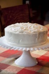 Whipped Cream Cake on milk glass plate by wooden chair BakeThisCake recipe Photo by LifeForcePhotoscom